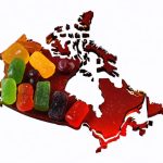 A collection of vibrant CBD gummies in the shape of Canada, symbolizing the expansion of the CBD gummies market with graphics showing upward trends and compliance icons.